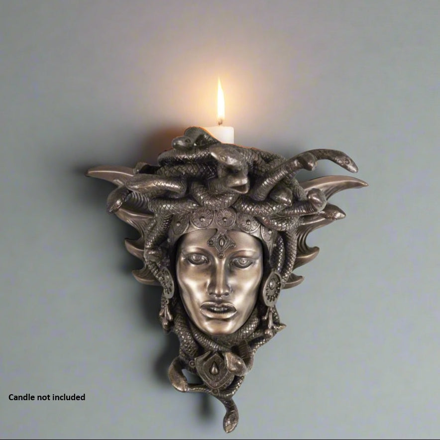Decorative wall sconce with Medusa head design on a plain background