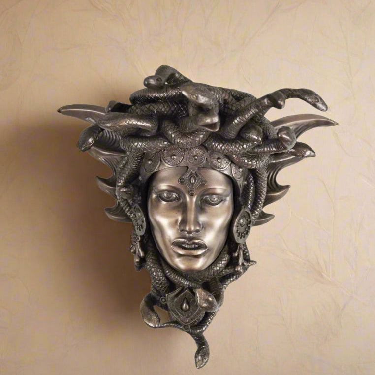 Decorative wall mask with a face and snake hair on a white background
