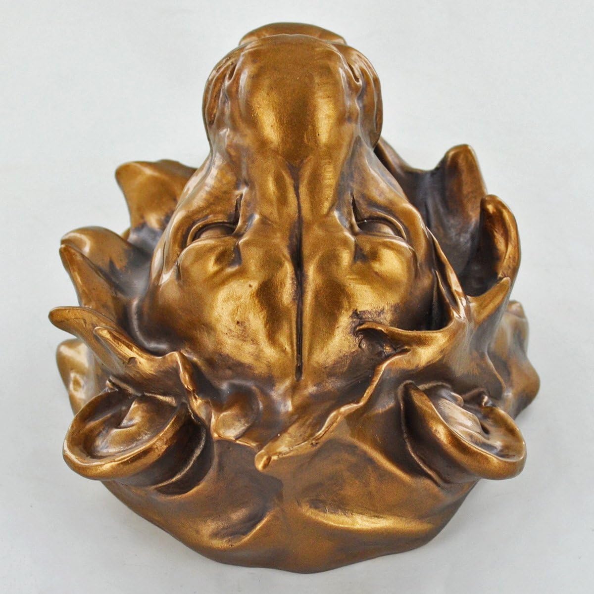 Bronze sculpture of a face on a white background