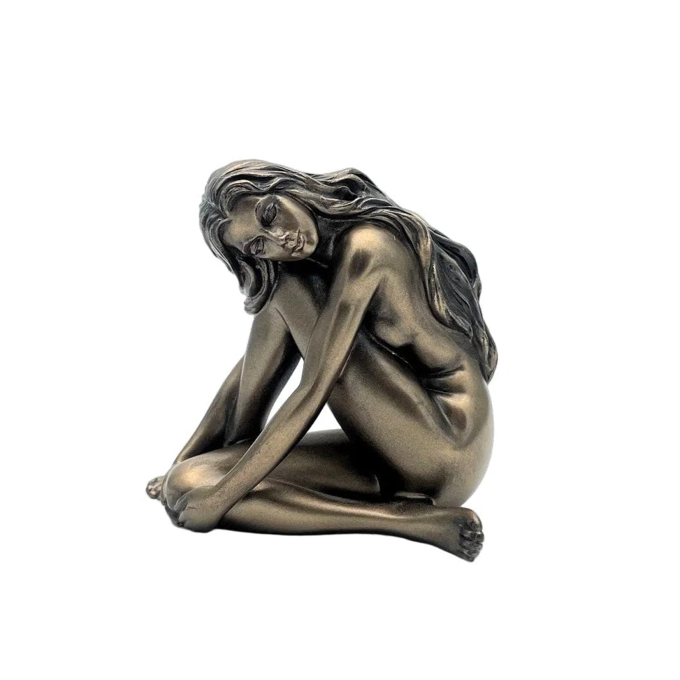 Bronze statue of a nude figure sitting on a white background