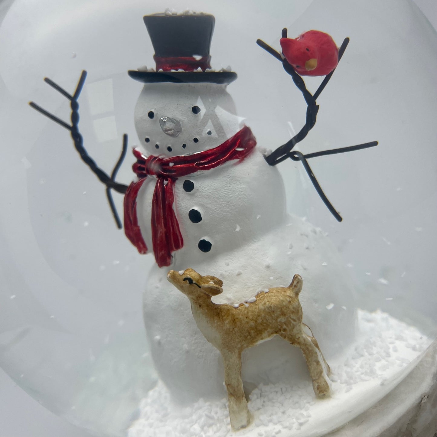 Snowman figurine with a deer and red scarf inside a snow globe