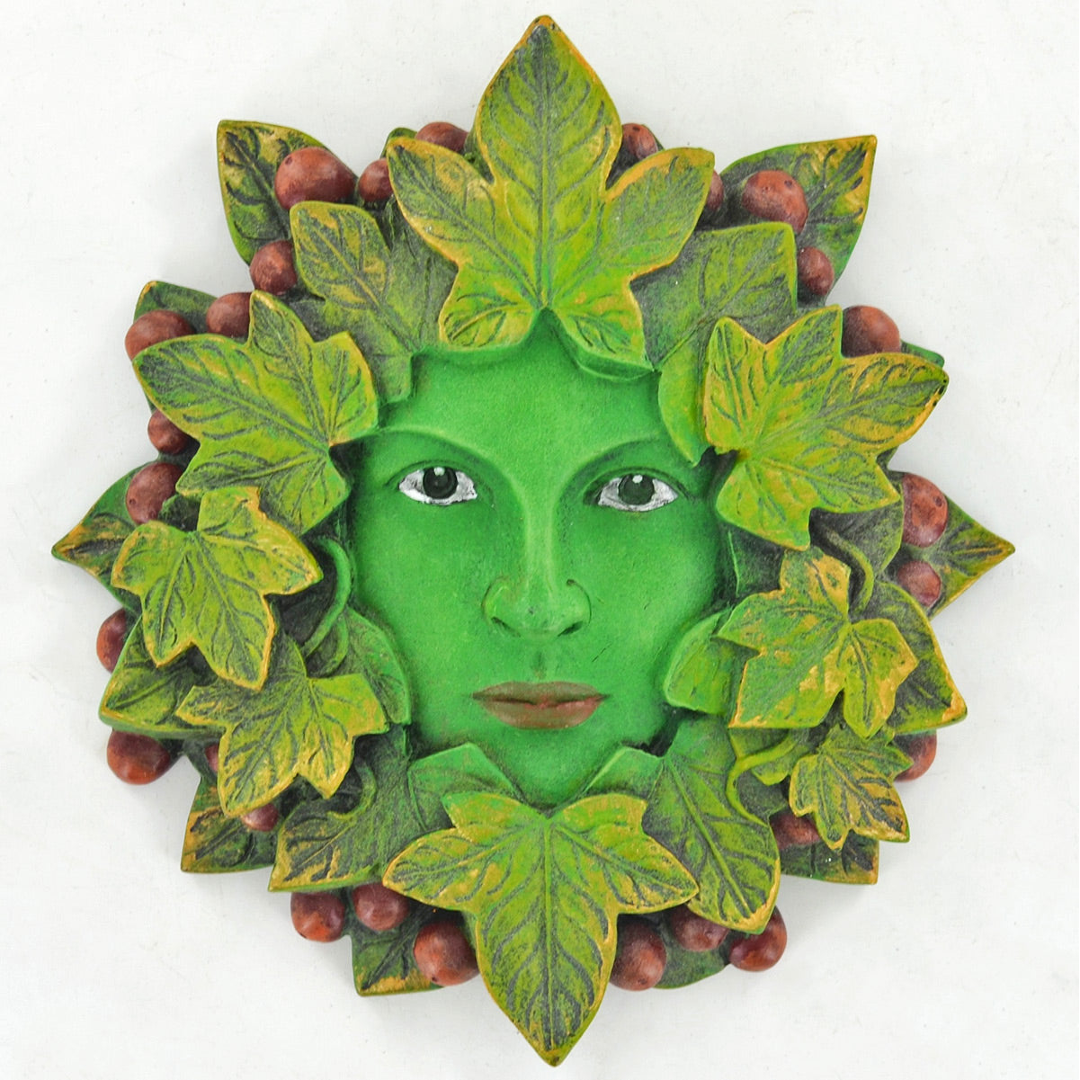 A decorative green tree of life wall plaque featuring a stylized human face surrounded by leaves and small berries, shown against a plain white background.