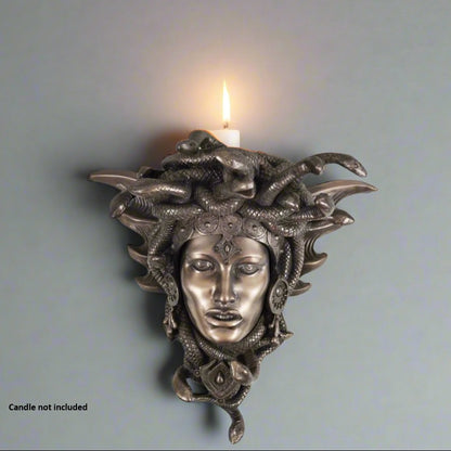 Decorative wall sconce with Medusa head design on a plain background