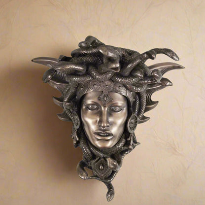 Decorative wall mask with a face and snake hair on a white background