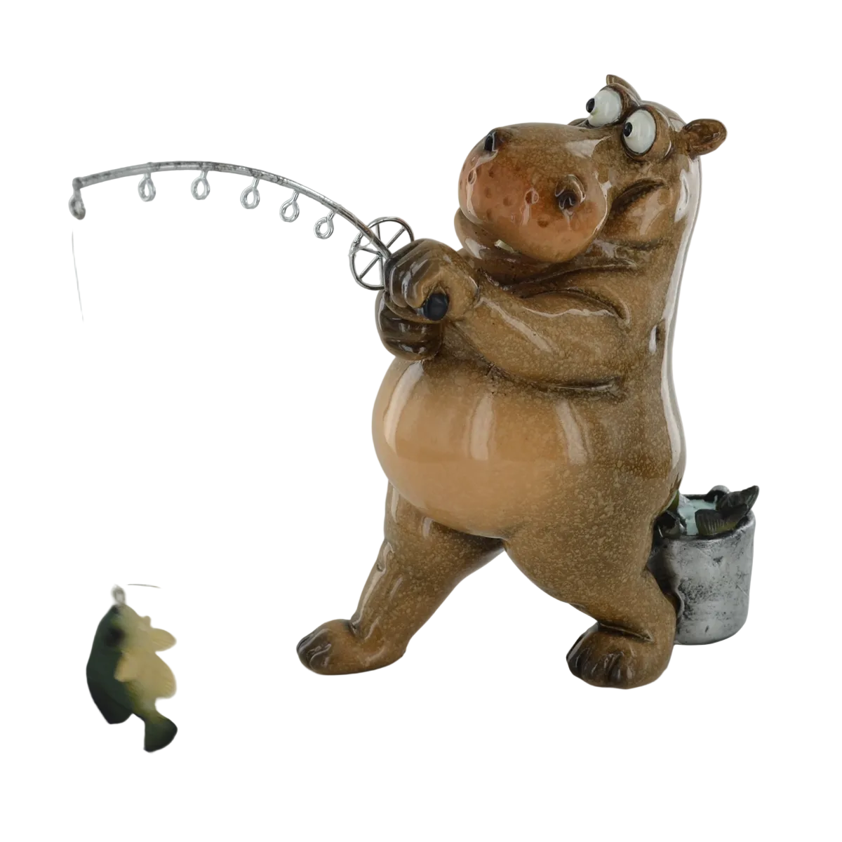 A ceramic hippo figurine holding a fishing rod with a dangling fish lure, standing next to a small bucket on a light gray background.