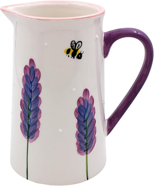 A white ceramic pitcher with a purple handle, a pink rim, and hand-painted purple lavender flowers and a small bee on the front.