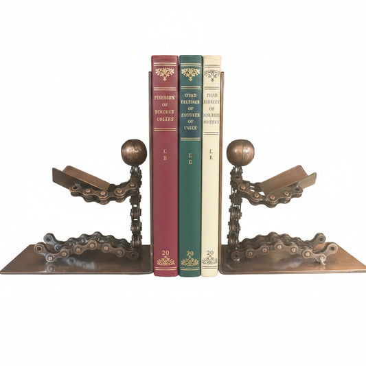 A pair of rustic metal bookends shaped like people reading made from chains with figures reading