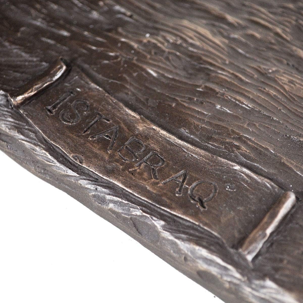 Close-up of a bronze object with 'ISTABRAQ' engraved on it.