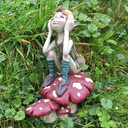 Gnome figurine sitting on a mushroom in a grassy area
