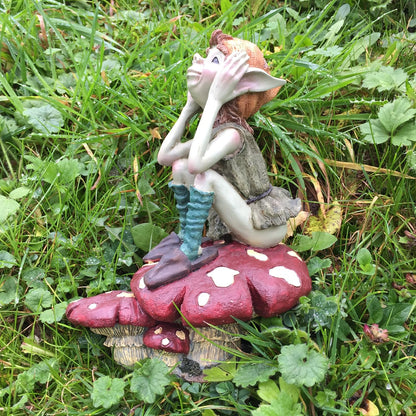 Gnome figurine sitting on a mushroom in a grassy area