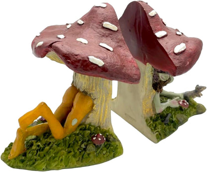 Pixie house made of two large mushrooms with a pixie laying in it, on a white background.