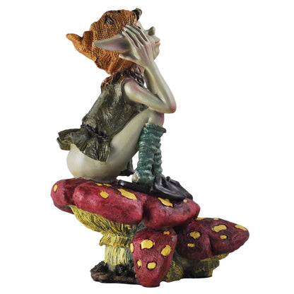 pixie figurine sitting on a mushroom with a seashell on a white background