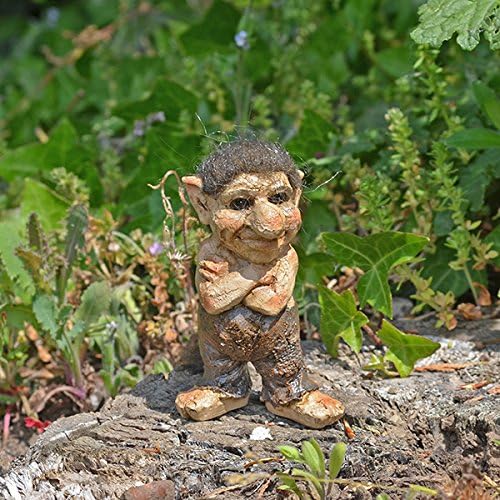 Small troll garden gnome figurine on a rock with green foliage in the background